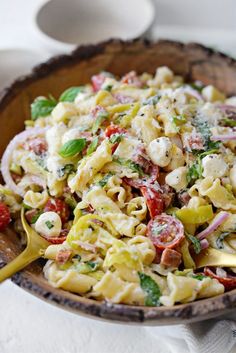 a wooden bowl filled with pasta salad on top of a table