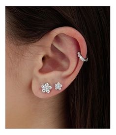 a woman wearing three flower shaped ear piercings on her left and right side of the ear