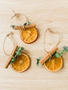 three orange slices with cinnamon sticks tied to them