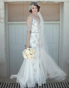 a woman in a wedding dress holding a bouquet and posing for the camera with her veil over her head