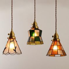 three lamps hanging from the ceiling with one light turned on and two lights off in different colors