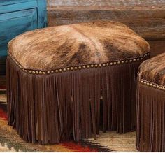 a brown ottoman with fringes on it and a blue door in the back ground