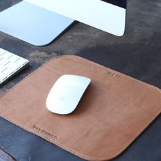 a leather mouse pad with a white computer mouse on it and a keyboard next to it