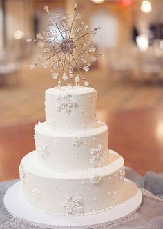 a white wedding cake with snowflakes on top