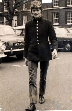 an old black and white photo of a woman walking down the street with her hand in her pocket