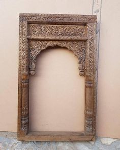 an old wooden frame with carvings on the outside and inside is leaning against a wall