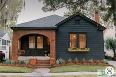 a small house with a black front door and brick steps leading to the front porch