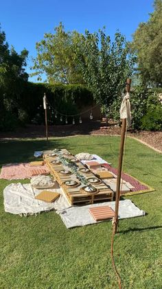 an outdoor picnic table is set up in the grass with several plates and bowls on it