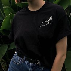 a woman wearing a black t - shirt with an airplane embroidered on it