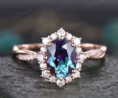 an oval shaped blue and white diamond ring on top of a rock with diamonds around it