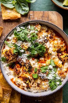 a bowl of mexican food with tortilla chips and cilantro on the side