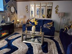 a living room filled with blue couches and gold mirrors on the wall above them