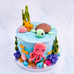 a blue cake decorated with an octopus, turtle and starfish on a white background