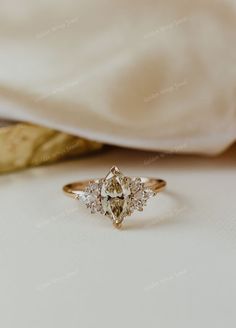 a diamond ring sitting on top of a white cloth next to a piece of fabric