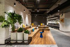 an office lobby with couches, tables and planters on the sidelines in front of a white brick wall