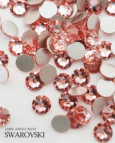 pink and silver sequins are scattered on a white surface with the words swarovski above them