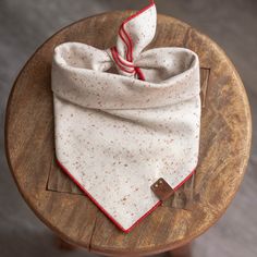 a white and red polka dot bandana on a wooden table with a leather tag