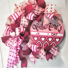 a pink and red valentine's day wreath hanging on a door