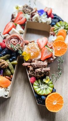 a letter made out of fruits and vegetables on a wooden table with an orange slice