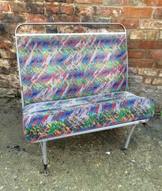 a colorful bench sitting next to a brick wall