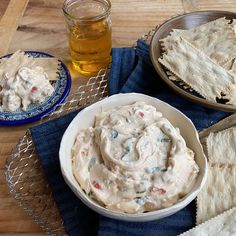 a bowl of dip next to crackers and a glass of beer