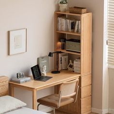 a bedroom with a bed, desk and bookshelf next to a white wall