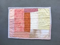 a piece of cloth is laying on the ground with an orange and pink patchwork design