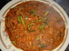 a white plate topped with meat and veggies covered in gravy on top of a table