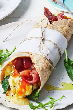 a wrap filled with meat and vegetables on top of a plate