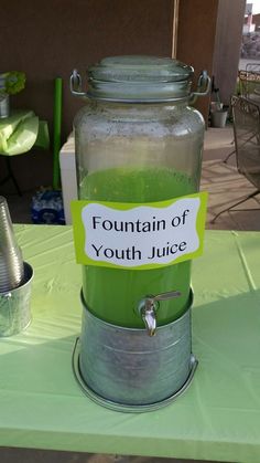 a green liquid in a glass jar with a sign on it that says fountain of youth juice