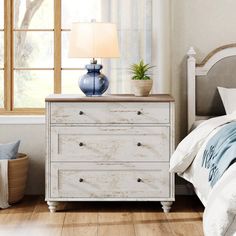 a white dresser sitting next to a bed in a bedroom on top of a hard wood floor