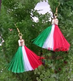 two red, white and green tasselled earrings hanging from gold - plated hooks