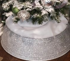 a white christmas tree with silver ornaments and snowflakes on it's top