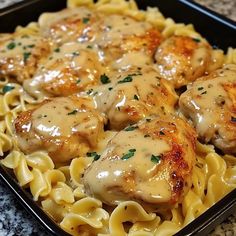 chicken with gravy on top of pasta in a black dish sitting on a granite countertop