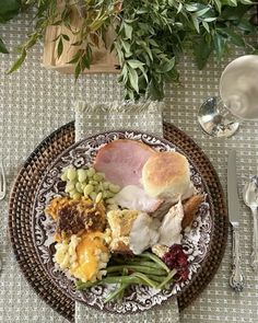 a dinner plate with ham, green beans and bread on it next to silverware