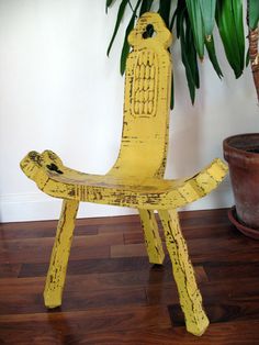 a yellow chair sitting on top of a wooden floor next to a potted plant