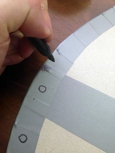 a person using a pen to cut out the pattern on a piece of paper