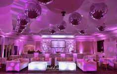 a room filled with lots of white couches and balloons hanging from the ceiling above