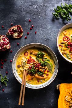 two bowls filled with soup and garnished with pomegranates on a black surface