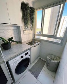 a kitchen with a washer and dryer in it next to a window filled with plants