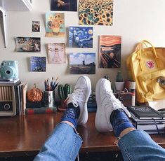 a person's feet resting on a desk in front of many pictures