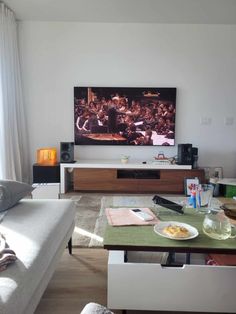 a flat screen tv sitting on top of a wooden table in front of a window