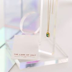 The Ames emerald amulet necklace features a golden amulet set with a sparkling CZ emerald baguette. It's a stunning and sophisticated addition to any ensemble. Adjustable 15-18" in length 11mm x 8mm pendant (approx) Comes packaged on a necklace card Hypoallergenic Heavy 18k Gold Plate over brass with e-coating for extra longevity ** Our pieces are plated 1 micron thick, industry standard is .125. Quality & longevity are extremely important to us. We wanted to ensure these pieces will last and wo Amulet Necklace, Emerald, 18k Gold, Gold Plate, Sparkle, Plating, Brass, Pendant, Gold