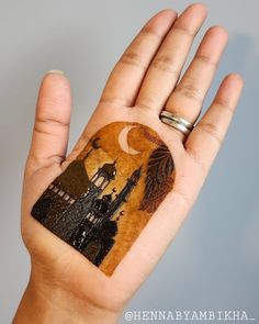 a person's hand holding a piece of wood with an image of a castle on it