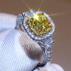 a fancy yellow diamond ring sitting on top of a white cloth with the sun shining through it