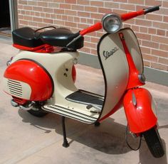 a red and white scooter parked next to a brick building