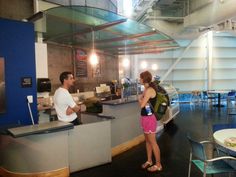 a man and woman standing in front of a counter talking to each other at a restaurant