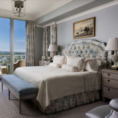 a large bed sitting in a bedroom next to a window with curtains on both sides