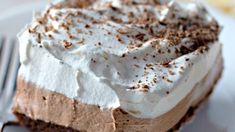 a piece of cake with whipped cream and chocolate shavings on top is sitting on a plate