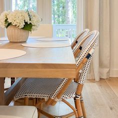 a dining room table set with place settings and flowers in a vase on the table